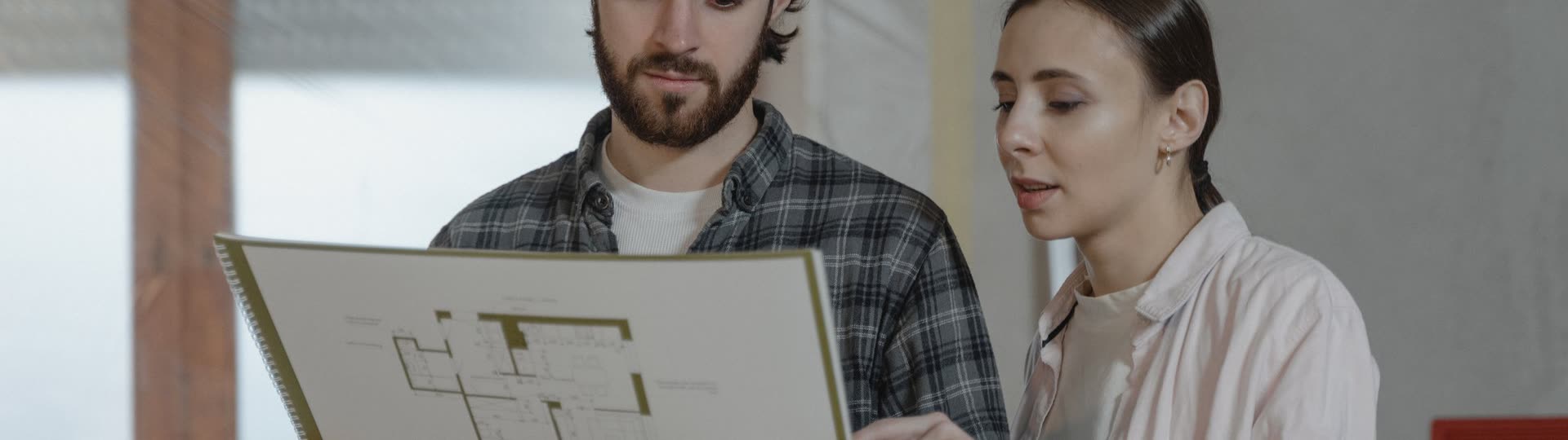 Två personer går igenom en ritning under en renovering.